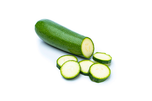 Close up of a ripe zucchini with slices isolated on white background. Predominant colors are green and white. High resolution 42Mp studio digital capture taken with SONY A7rII and Zeiss Batis 40mm F2.0 CF lens