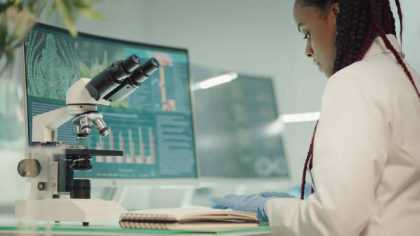 istock African ehtnicity female scientists checking medical marijuana, making notes. Team in background. Laboratory tests on screens. 1318680615