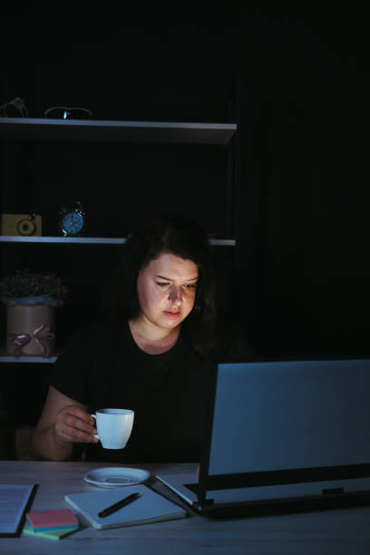 istock Focused woman working at laptop at night 1318681327