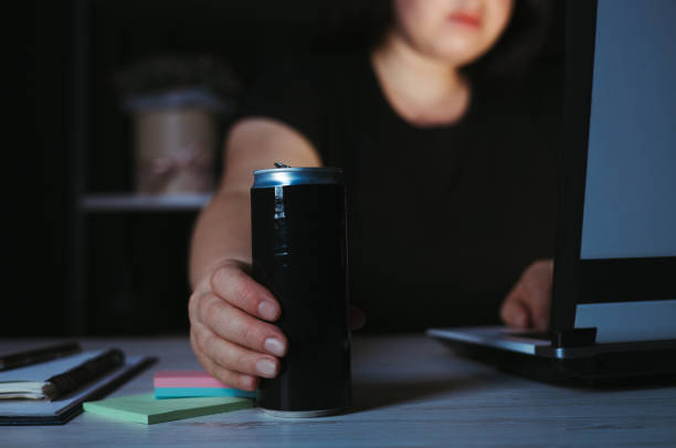 Focused woman drinking energy drink at night Focused woman holding and energy drink in the night. Deadline project, overworking, freelance worker energy drink stock pictures, royalty-free photos & images