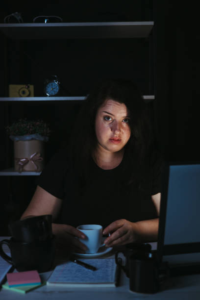 istock Young focused woman doing overtime job at night 1318681360