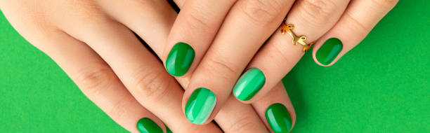 istock Beautiful groomed woman's hands with spring summer nail design on green background 1318681670