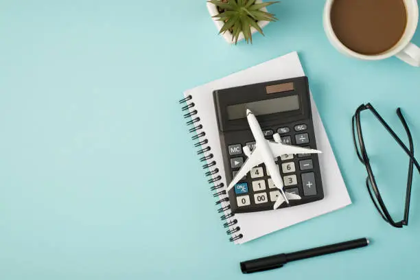 Top view photo of aircraft model on calculator cup flowerpot organizer pen glasses on isolated pastel blue background with copyspace