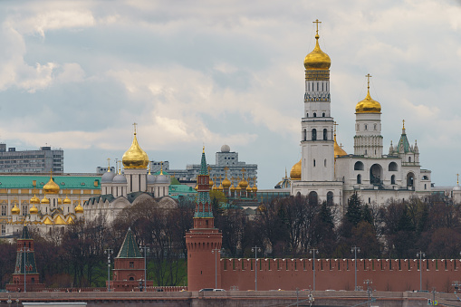 Moscow downtown cityscape. Kremlin Towers, Ivan the Great Bell Tower, Dormition Cathedral in spring day. Majestic domes.Road is filled out buy cars. Rush hours