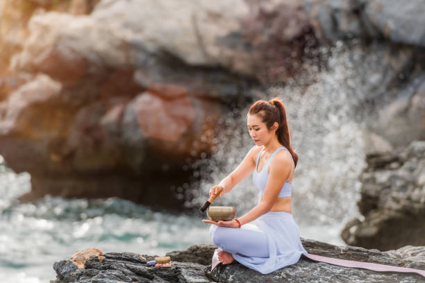 bela mulher asiática está praticando meditação yoga por tigela de canto tibetano - tibetan culture music sound recovery - fotografias e filmes do acervo