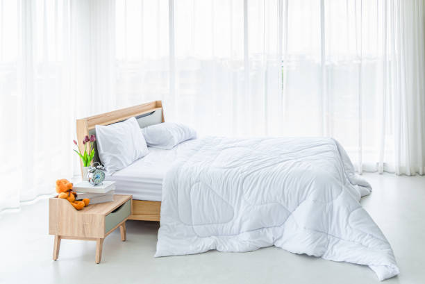 istock Interior white bedroom with white curtains and white pillows on wooden bed 1318683737