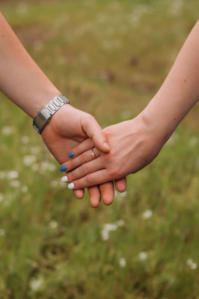 istock loving couple holding hands close up on blurred background 1318684309