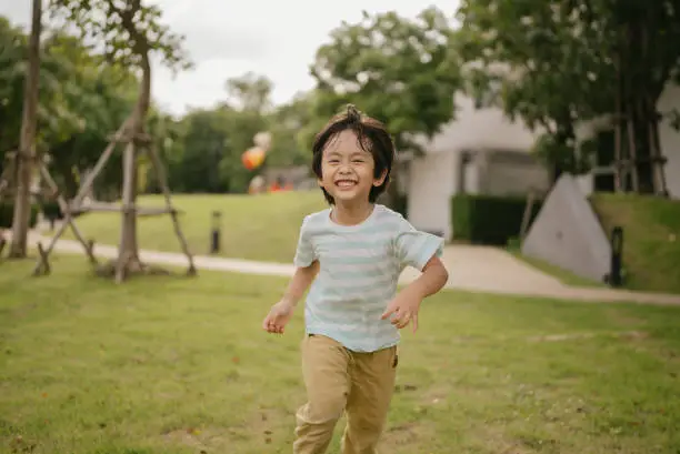 Photo of Asian boy running in park.