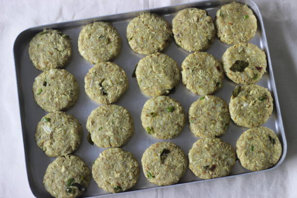 a small flat cake of minced chicken with herbs and spices ready to fry. prepared for making chicken cutlets - cutlet imagens e fotografias de stock