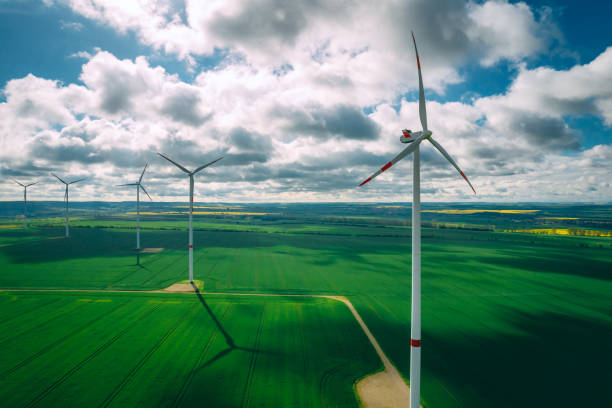 istock wind turbines and agriculture field against clouds 1318687346