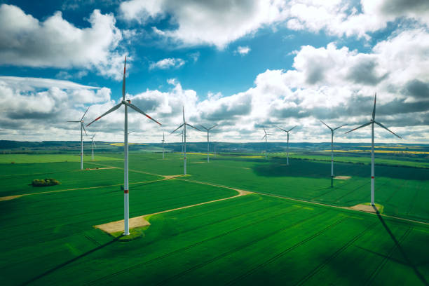istock wind turbines and agriculture field against clouds 1318687374