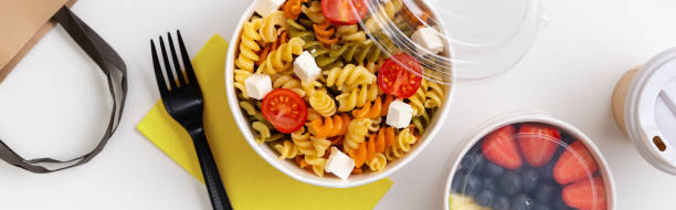 istock Pasta, coffee and fruits in taking away boxes on white table. 1318687541
