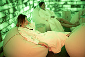 Two women in bathrobe sitting and relaxing in salt room