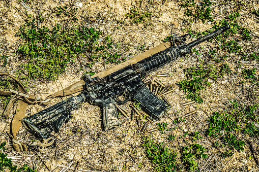 A modern automatic American carbine lying on the ground in the mud. Weapons in extreme conditions. Testing weapons for strength, performance and practicality.