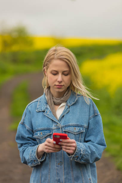 istock Beautiful blonde in denim jacket with mobile phone 1318691550
