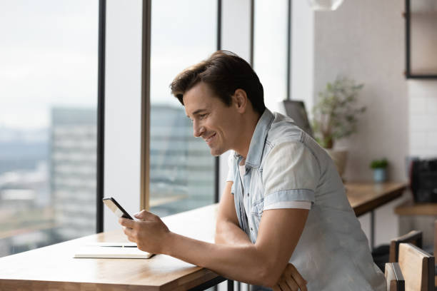 istock Smiling man use smartphone texting online on gadget 1318692285
