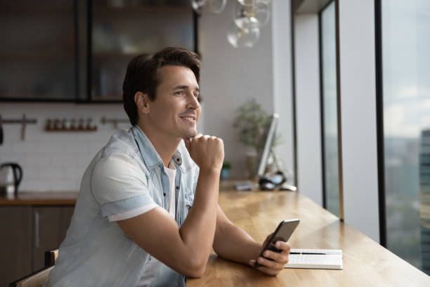 istock Pensive man use smartphone look in distance thinking 1318692292