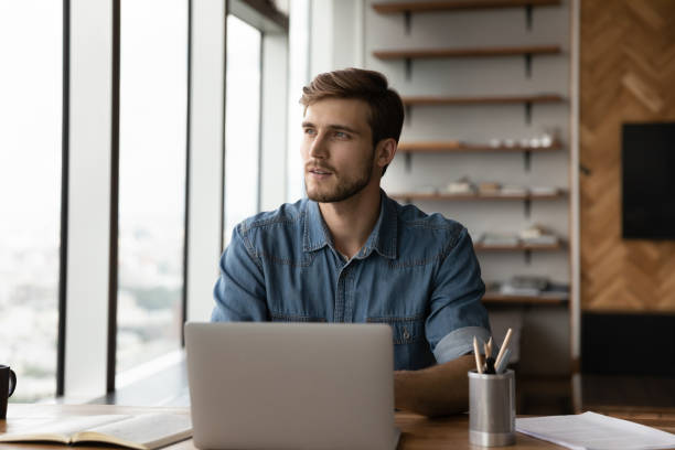 Pensive Caucasian man work on laptop thinking