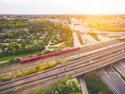 Electric city train running on rails next to the car traffic in in Copenhagen, Denmark. Aerial view shot with drone at Lyngbyvejen. Public transportation by train and bus are together with bicycling the fastest way to to get to work in this capital. The sustainable electric train contrasts the busy highway that cuts through central Copenhagen