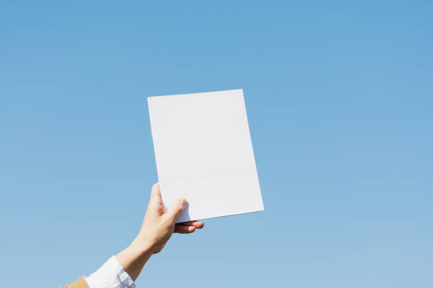 istock A female hand holds a book in a white cover on a blue background 1318698420
