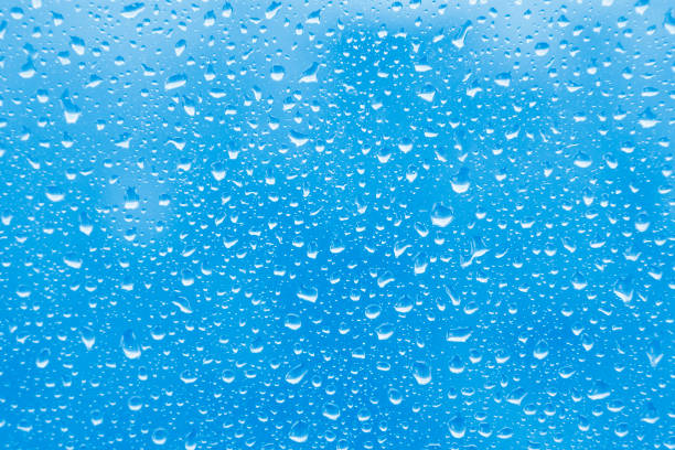 istock Water rain drops on blue glass surface as background. Abstract backdrop. 1318698840