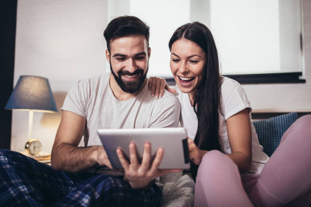 istock Young couple using tablet in a hotel room while lying on the bed. 1318699615