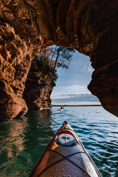 Apostle Islands Two Kayakers 02 The Apostle Islands National Lakeshore in Wisconsin host some of the most beautiful sea caves in the US. Here two kayakers make their way through the cliffs and tunnels carved by Lake Superior. bayfield county stock pictures, royalty-free photos & images