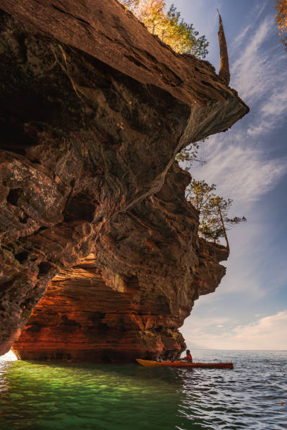 Apostle Island Sea Cave Kayaker A lone kayak enters one of the Apostle Island National Lakeshore Sea Caves in Wisconsin. bayfield county stock pictures, royalty-free photos & images