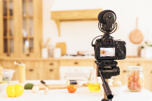 istock Recording a culinary blog on camera. Blurred light kitchen interior and table with groceries. Copy space 1318704664