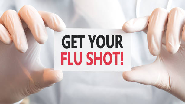 istock doctor holding a card with text get your flu shot, concept 1318707679