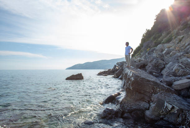 istock Man relaxes on rocky coastline at sunrise 1318711353