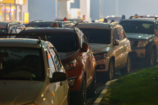 cars stuck in traffic jam at gas station at foggy night during supply crunch - close-up with selective focus