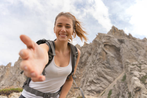 joven en la cima de la montaña, extendiendo la mano para ayudarle a llegar a la cumbre - aspirations mountain hiking climbing fotografías e imágenes de stock