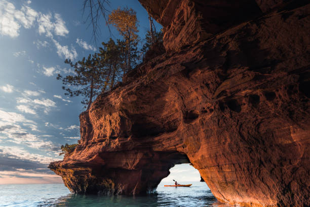 Apostle Island Sea Caves A lone kayaker exits a sea cave on The Apostle Island National Lakeshore in Wisconsin in Fall. wisconsin stock pictures, royalty-free photos & images
