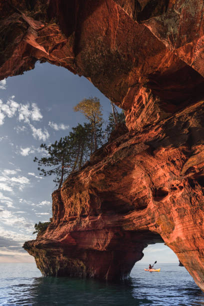 Apostle Island Sea Caves A lone kayaker exits a sea cave on The Apostle Island National Lakeshore in Wisconsin in Fall. bayfield county stock pictures, royalty-free photos & images