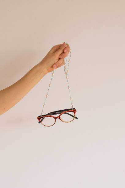 A woman's hand holds sight glasses on a handmade chain