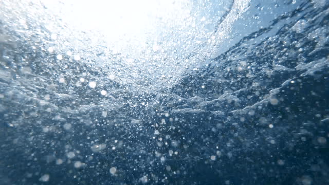 Slow motion footage of scuba diver releasing air during the dive. Air bubbles floating from sea botton to the water surface