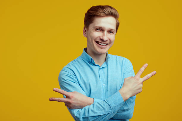 istock Young man dressed in blue shirt showing peace gesture with crossed hands 1318717186