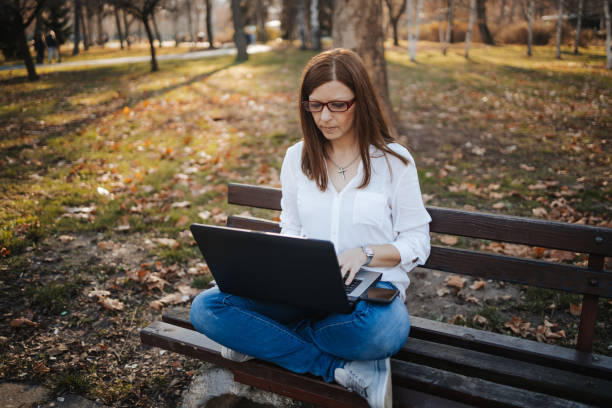 istock Young beautiful woman sitting on bench in public park 1318717852
