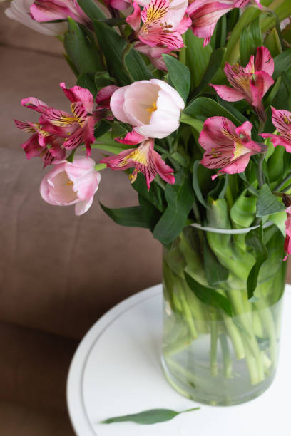 istock vase of pink flowers on white table 1318717973