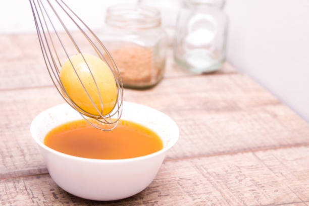 istock egg in a kitchen whisk immersed in paint, a yellow easter egg, jars on the background, copy space, wooden table, the process of preparing for Easter 1318720184
