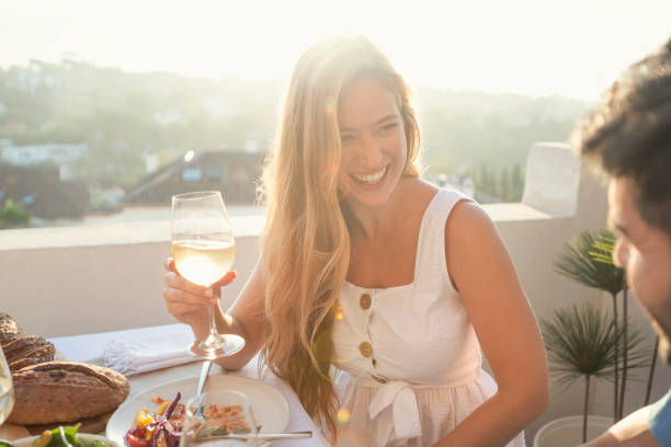 portrait of a couple enjoying a meal with friends outdoors at sunset. - wine dinner party drinking toast imagens e fotografias de stock