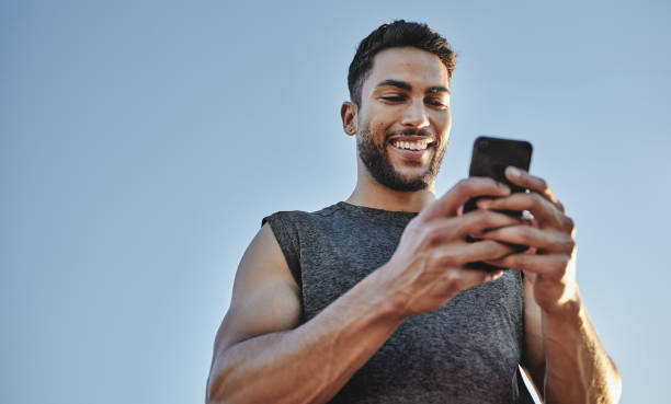 istock Low angle shot of a sporty young man using a cellphone while exercising outdoors 1318720531