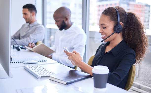 istock Shot of a young businesswoman using a cellphone while working in a call centre 1318721554