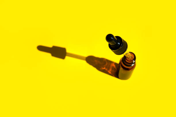 istock Cosmetics brown glass bottle with shadow and glass reflection on yellow background. Alternative care. Oil dropper illuminating spa bottle. The sun's rays, the shadows. selective focus 1318728704