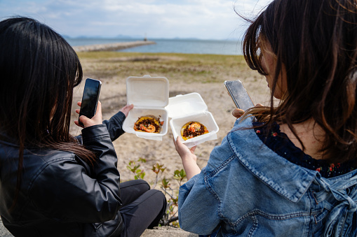 Young women taking photos of their lunch with a smart phone before enjoying it