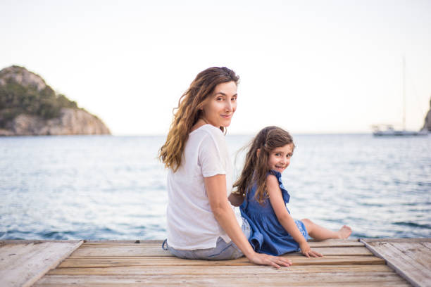 istock Smiling mother and daughter sitting and looking at camera 1318736952