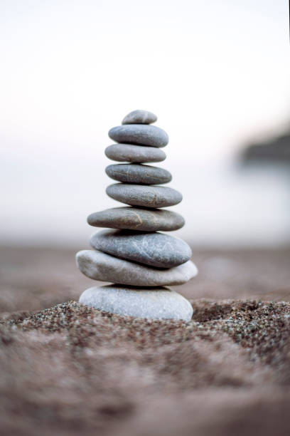 Vertical shoot of balanced pebbles on beach sand stock photo