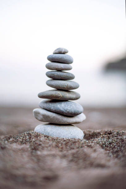 vertical shoot of balanced pebbles on beach sand - balance simplicity nature beach imagens e fotografias de stock