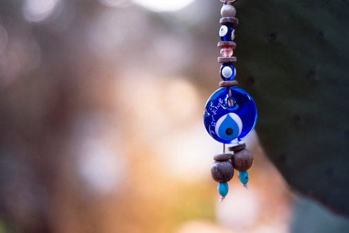 A hanged blue glass evil eye at sunset with Turkey text